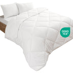 Weiße, gesteppte Mikrofaser-Steppdecke auf einem Bett mit zwei Kissen, OEKO-TEX zertifiziert.