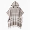 Formeya Poncho in Kaffeebraun. Eine Person entspannt damit auf einem gemütlichen Sofa zu Hause.