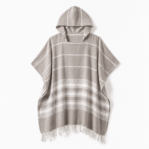 Formeya Poncho in Kaffeebraun. Eine Person entspannt damit auf einem gemütlichen Sofa zu Hause.