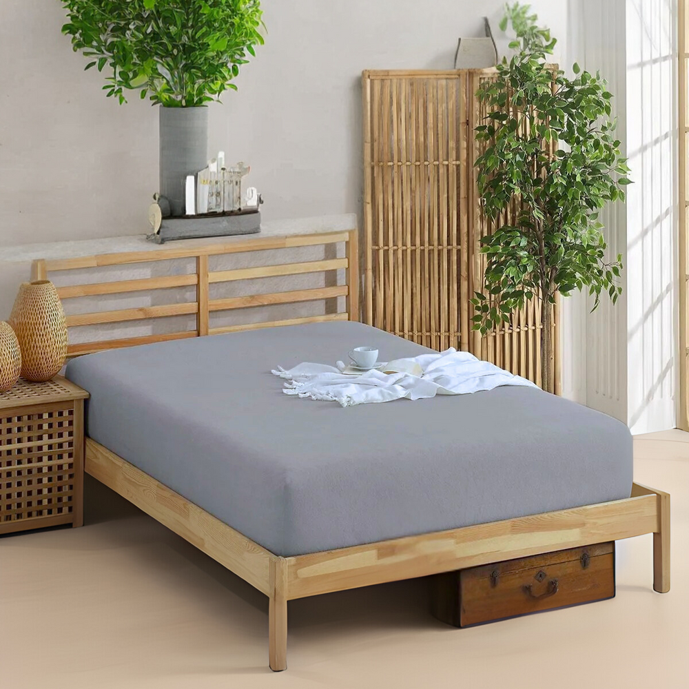 Graues Formeya Spannbettlaken aus 100 % Baumwolle auf einem Holzbett, atmungsaktiv und passgenau