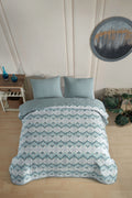 Betttextilien: Gesteppte Tagesdecke mit blau-weißem Zickzackmuster und passenden Kissen auf einem Bett in einem Schlafzimmer.