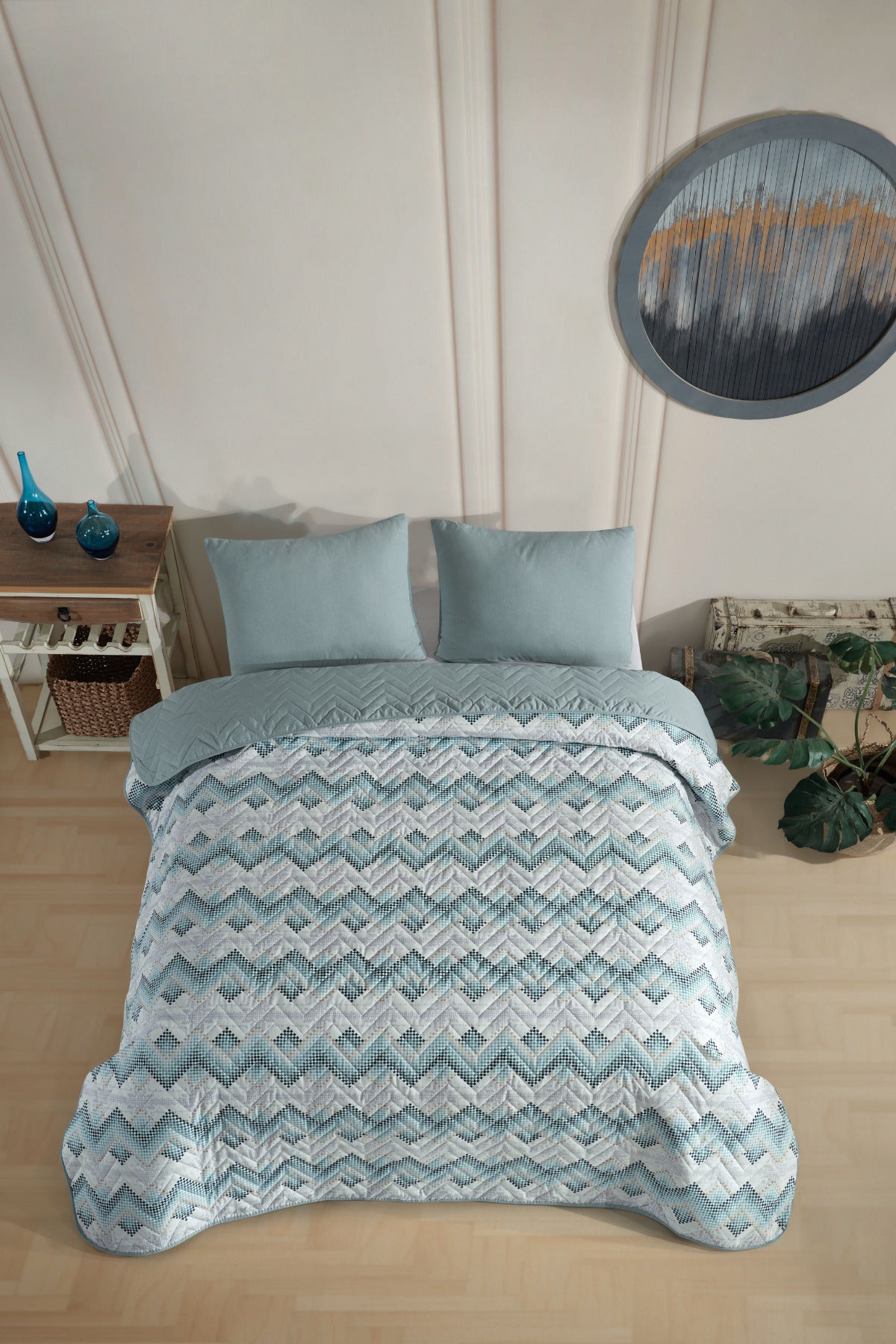 Betttextilien: Gesteppte Tagesdecke mit blau-weißem Zickzackmuster und passenden Kissen auf einem Bett in einem Schlafzimmer.