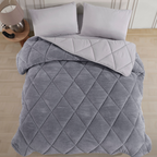 Luxuriöse, doppelseitige graue Wellsoft-Steppdecke mit Rautenmuster auf einem Bett mit hellgrauen Kissen.